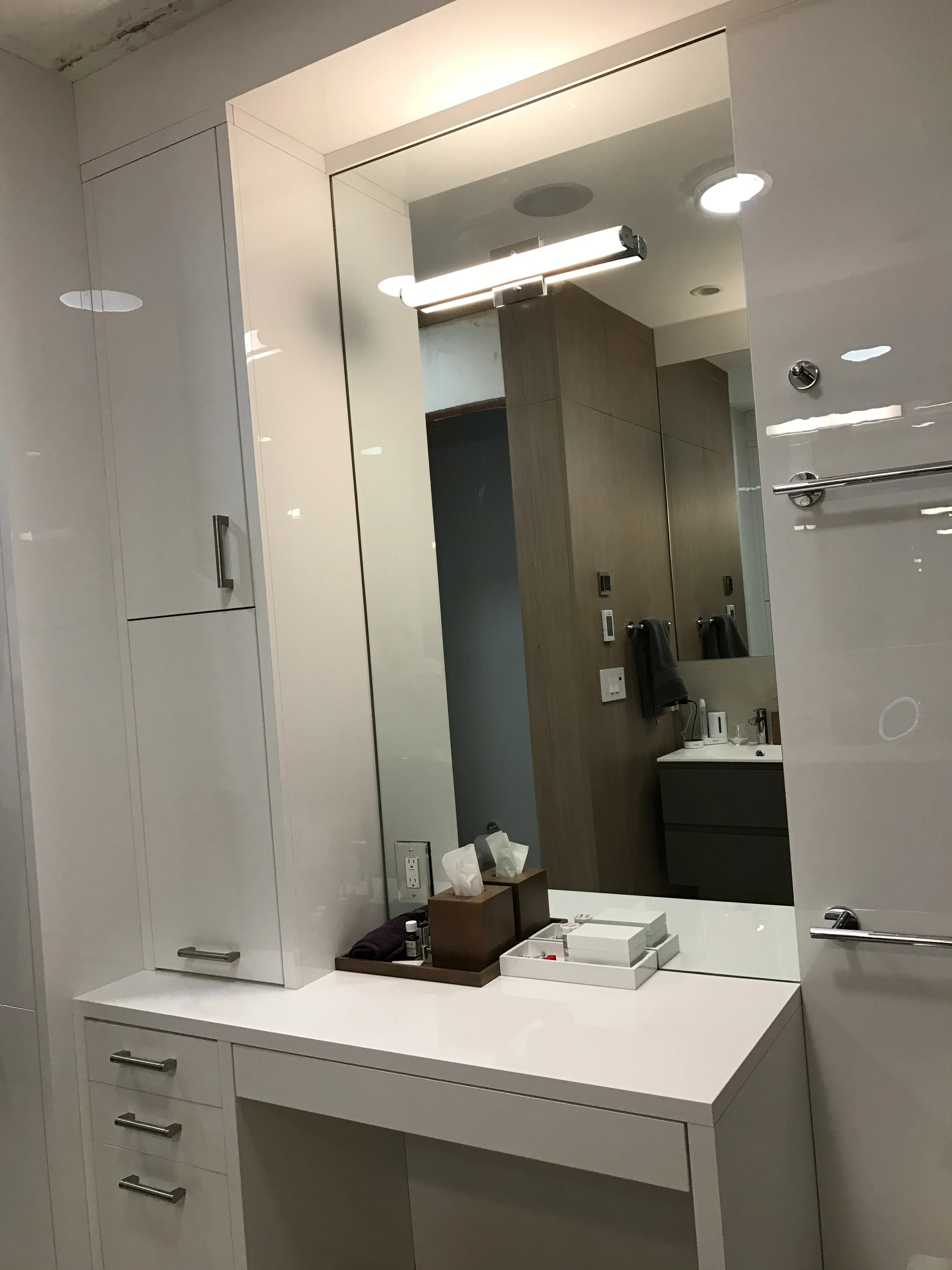 Finished bathroom vanity with glossy white cabinetry and custom panels