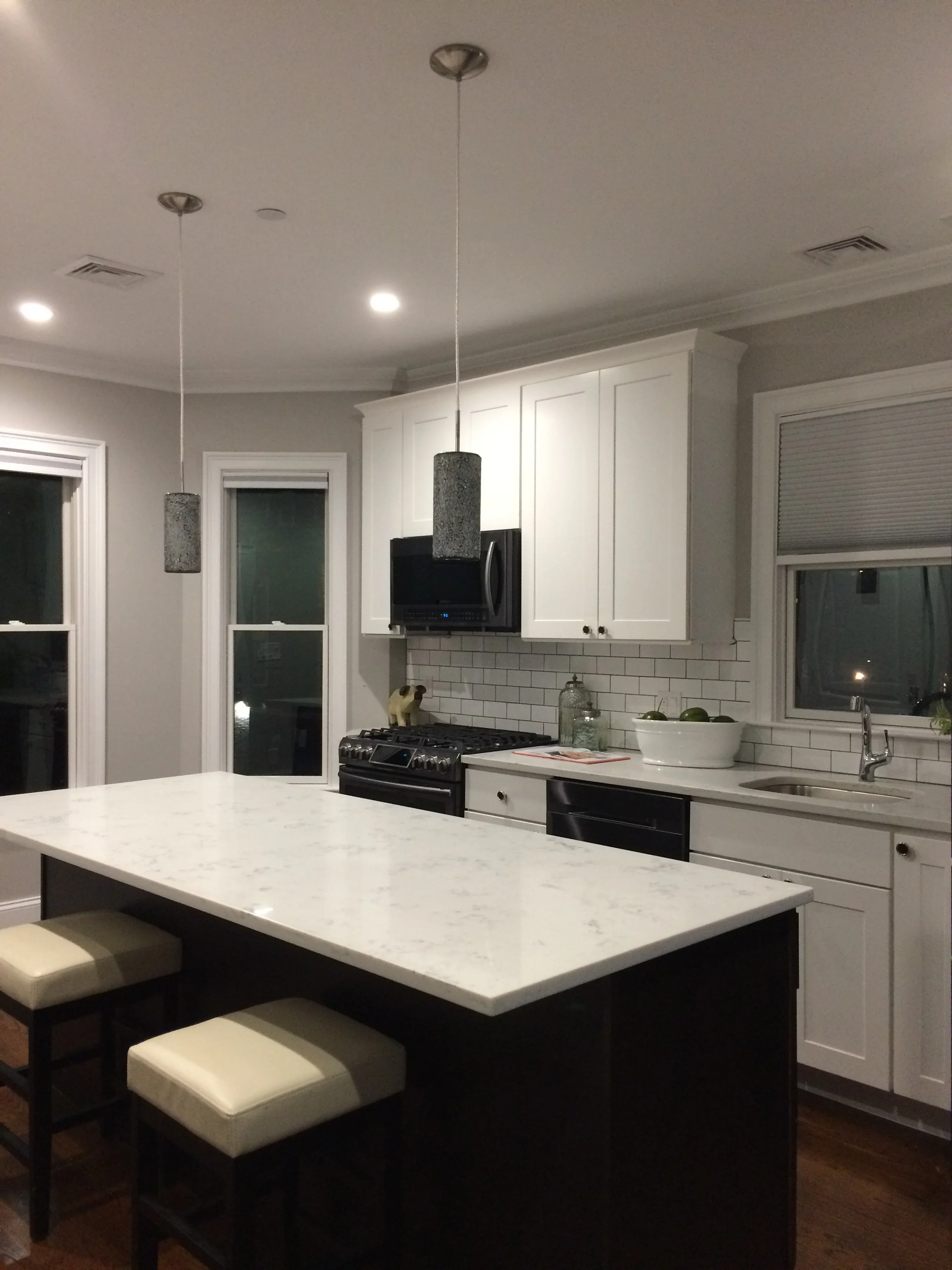 Finished kitchen with white cabinetry, crown molding and a large island