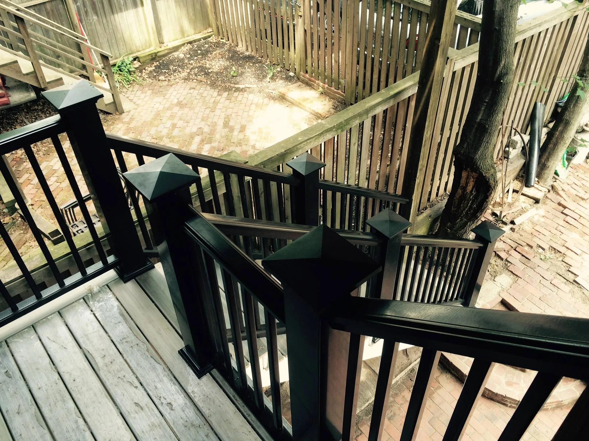Outdoor deck stair landing with black railings and composite boards