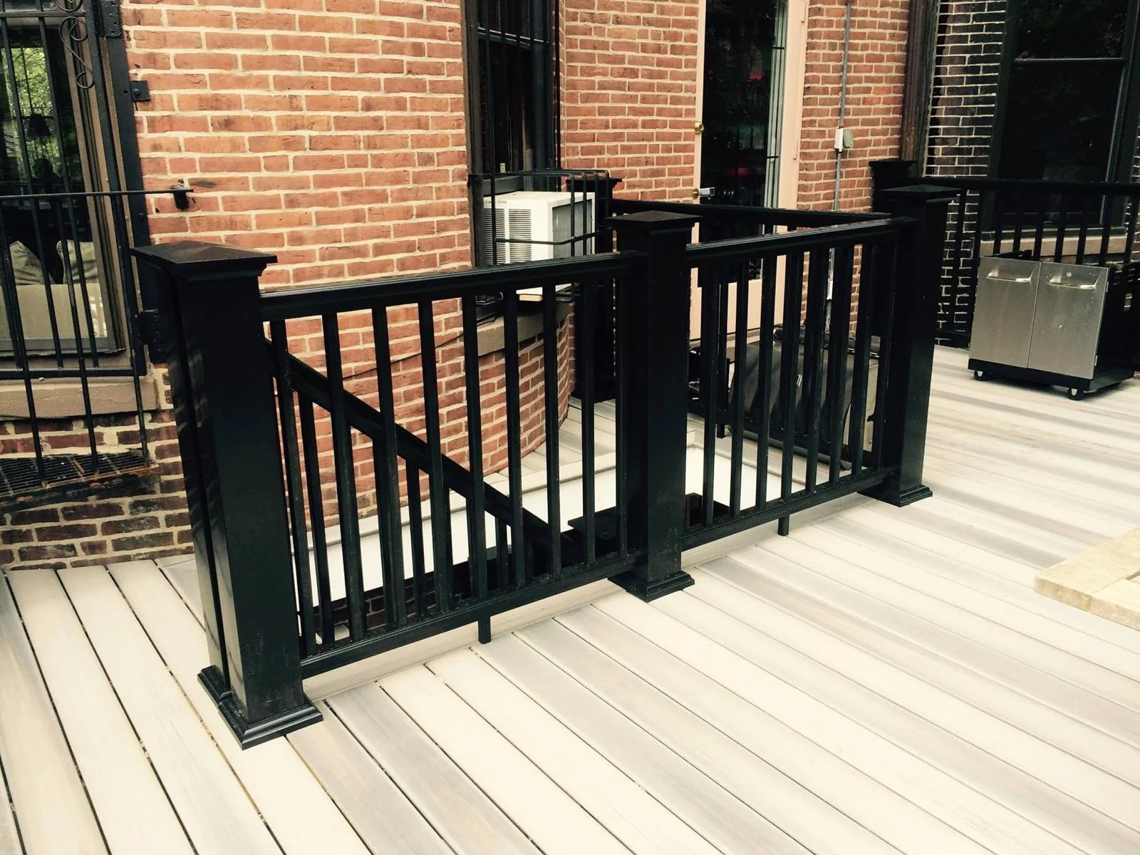 Urban composite deck with black railing and brick exterior